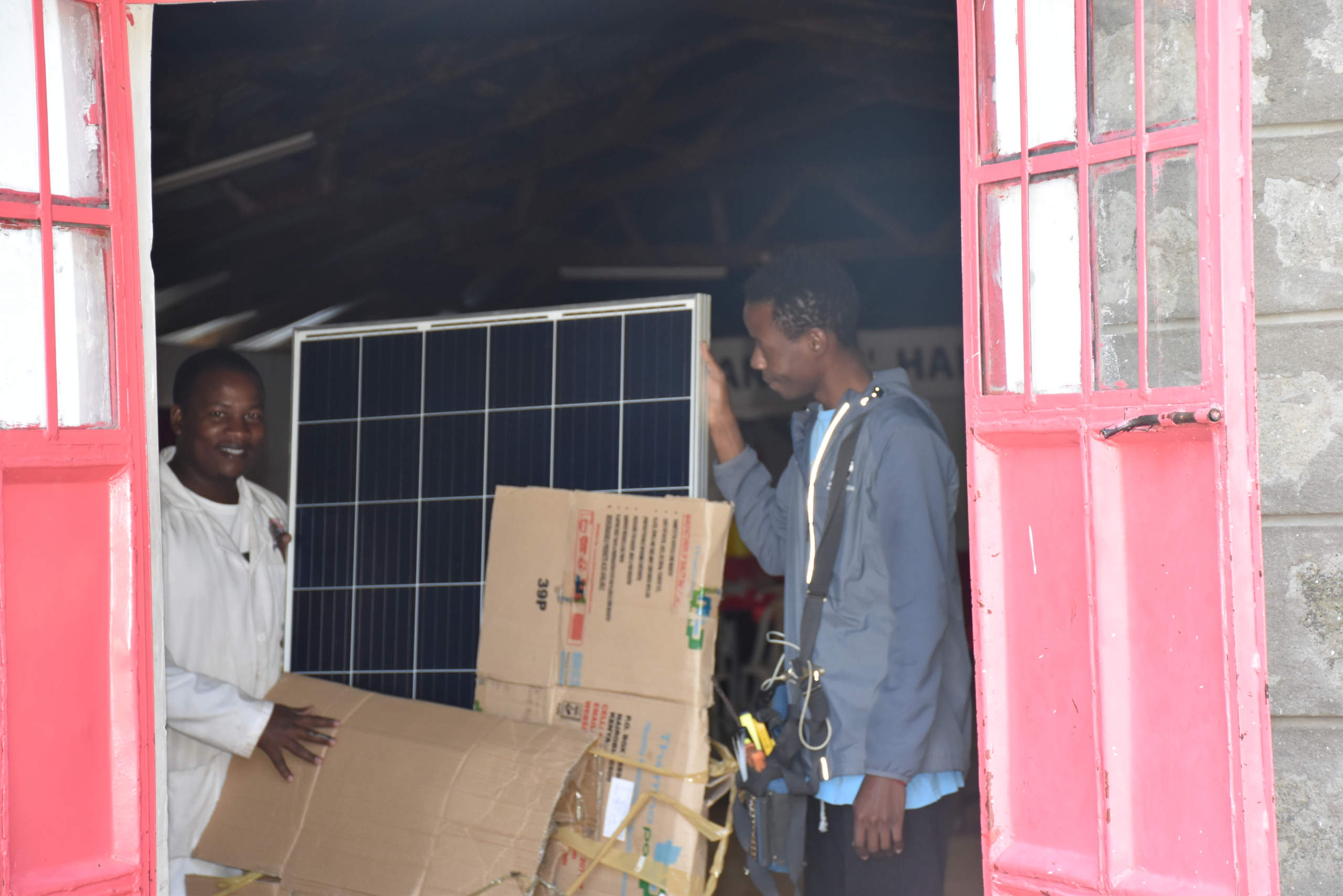 JAMS staff open a box of solar panels