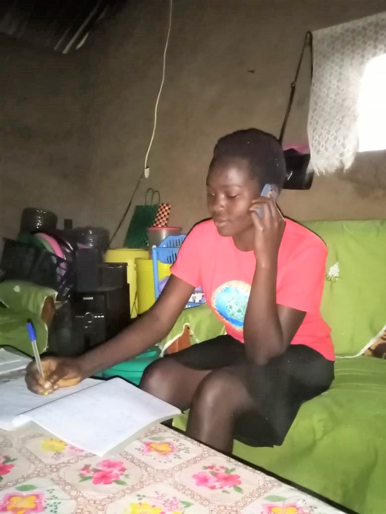 Form One student speaking with teacher from home Form 1 student on cell phone from her home, receiving assignments and feedback from her teacher at JAMS during the COVID shutdown.